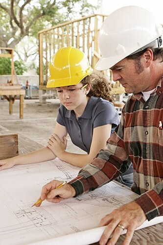 Image d'une apprentie et son tuteur travaillant sur le plan d'un bâtiment